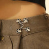 Close-up of a brown fabric waistband with silver floral buckles used as waist tighteners on a model's torso.