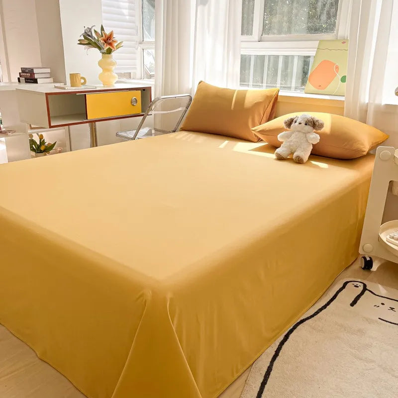 A bright yellow organic cotton bedding set displayed on a bed with a matching pillow and a small stuffed animal.