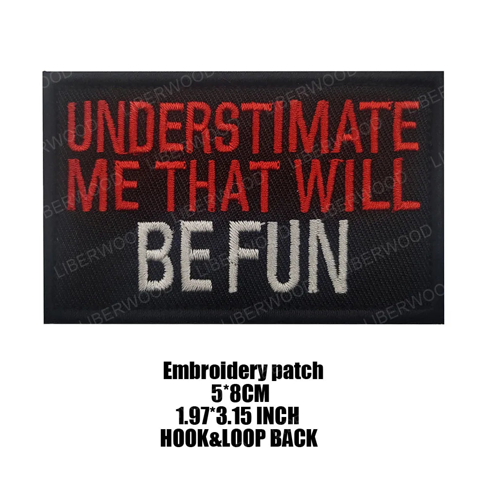 Black embroidered patch with red text that reads UNDERESTIMATE ME THAT WILL BE FUN