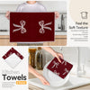 A set of two maroon kitchen towels with white bow designs being held by a person and placed on a plate.
