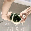 Hands are washing a leaf-shaped absorbent microfiber towel under running water.