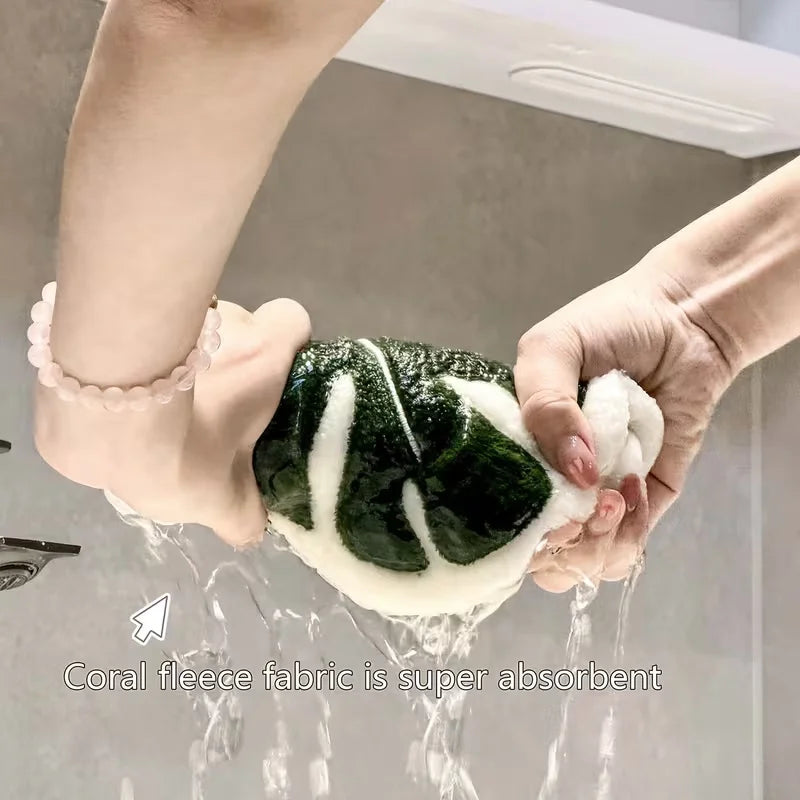 Hands are washing a leaf-shaped absorbent microfiber towel under running water.
