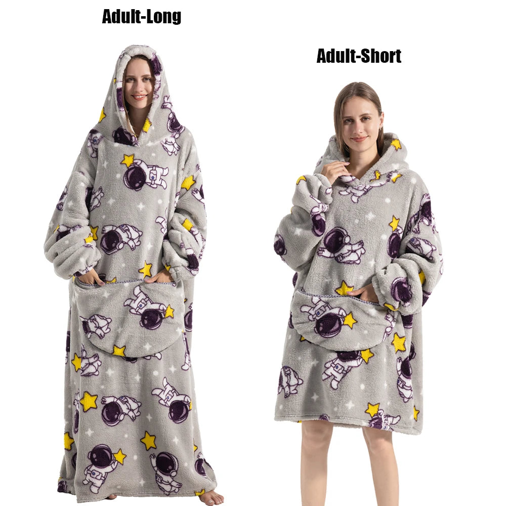 A gray plush fleece blanket hoodie with purple and yellow stars and astronaut designs shown on an adult model.