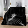 A black vintage-inspired graphic throw blanket draped over a white sofa.