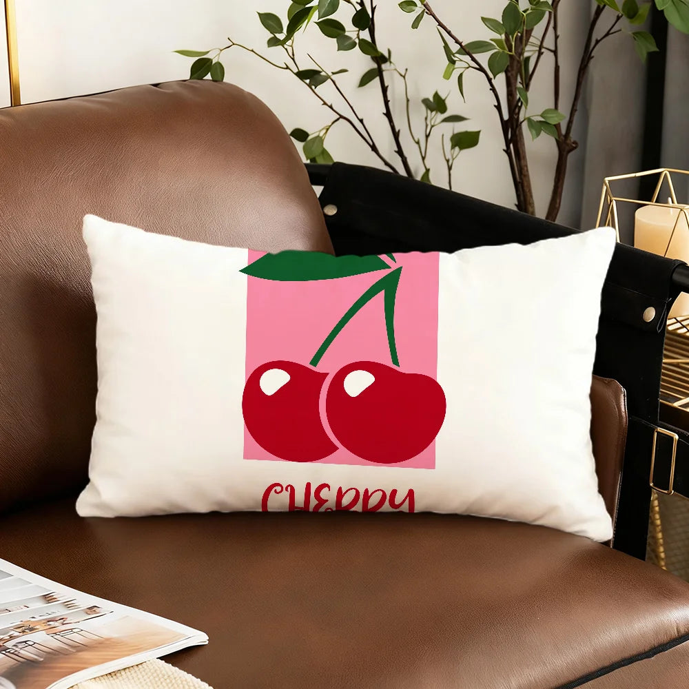A cushion cover featuring a cartoon illustration of two red cherries on a pink background.