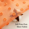Orange pompoms scattered on sheer fabric with a dark leaf detail