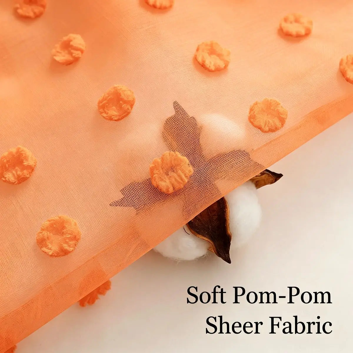 Orange pompoms scattered on sheer fabric with a dark leaf detail
