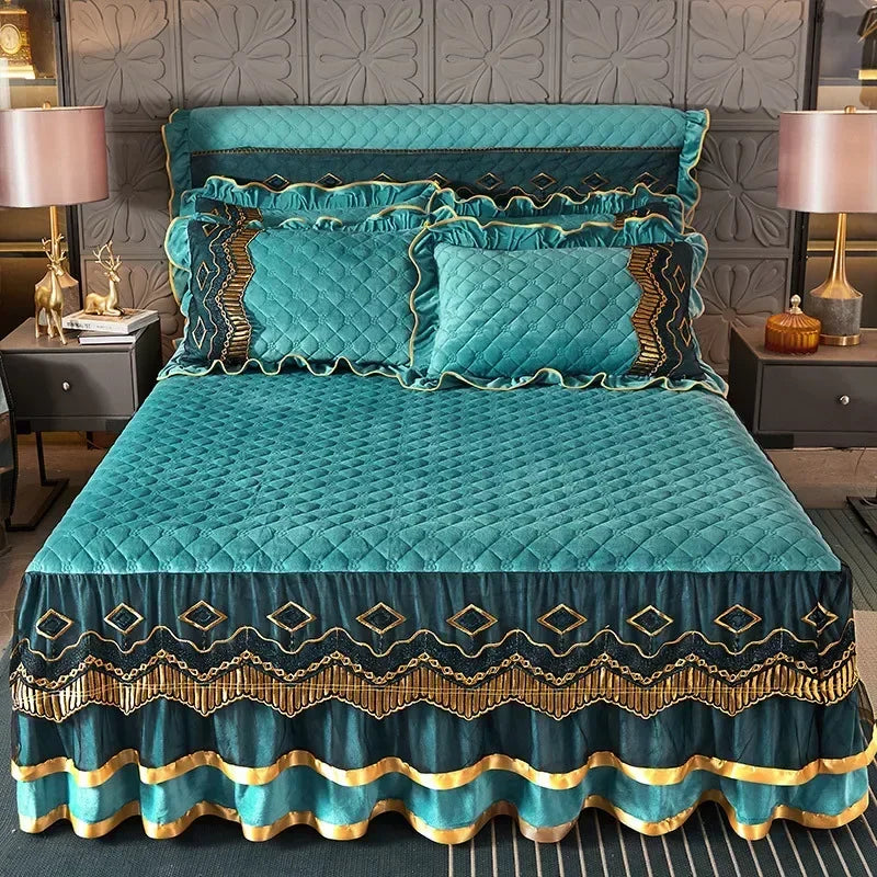 Teal velvet bed skirt with gold embroidery and diamond patterns on a quilted bed featuring a headboard.