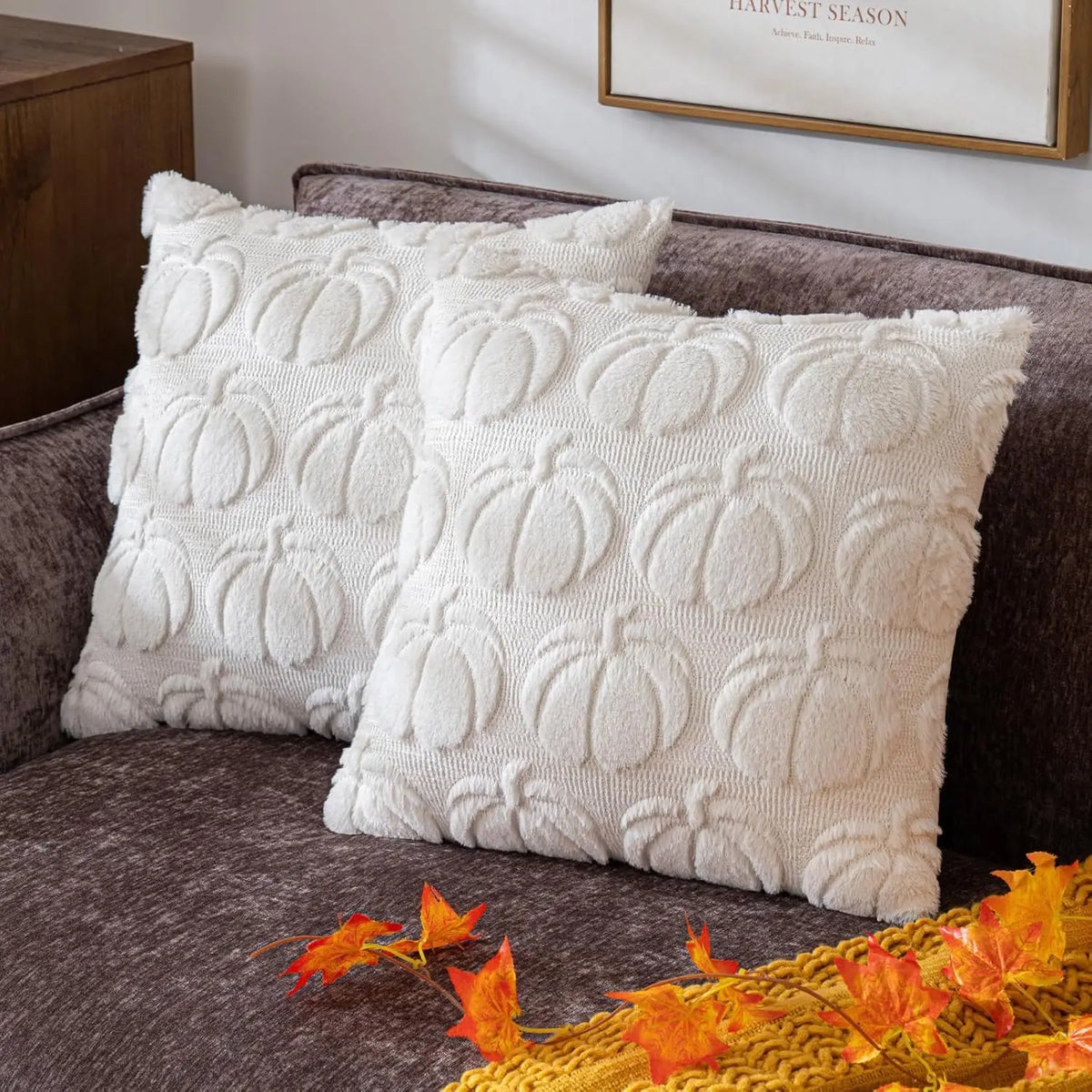 A white chenille throw pillow cover shaped like a pumpkin resting on a gray sofa.