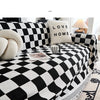 A black and white checkerboard sofa slipcover featuring a decorative throw pillow.