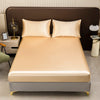 A beige satin bedding set featuring a mattress, pillows, and fitted sheets in a modern bedroom setting.