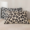 Two leopard print decorative pillow covers in black and beige are displayed on a light-colored sofa.