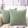 A close-up of a sage green corduroy striped throw pillow cover resting on a white sofa.