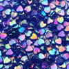 A close-up of iridescent blue and purple acrylic heart beads for jewelry making.