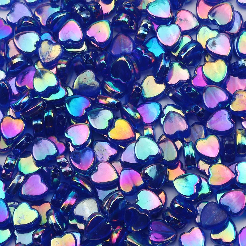 A close-up of iridescent blue and purple acrylic heart beads for jewelry making.