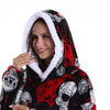 A woman smiling while wearing an oversized patchwork fleece hoodie with a black and red skull pattern.