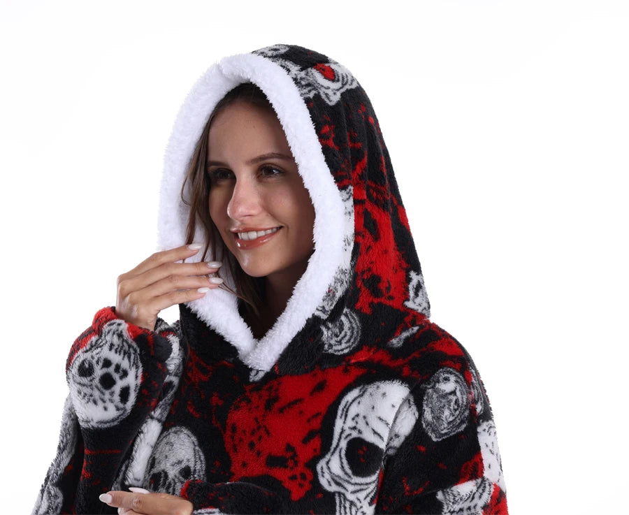 A woman smiling while wearing an oversized patchwork fleece hoodie with a black and red skull pattern.