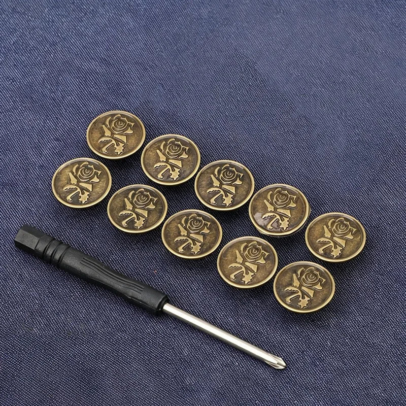 A set of ten antique gold-toned metal snap buttons with floral designs arranged on a dark blue fabric.