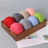 A wooden box filled with various colored mohair yarn balls including pink, red, gray, beige, blue, and green.