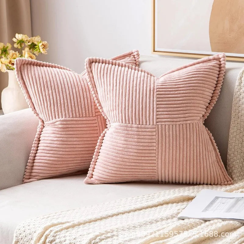 A pair of pink ribbed lumbar support pillows resting on a light-colored sofa next to a framed picture.
