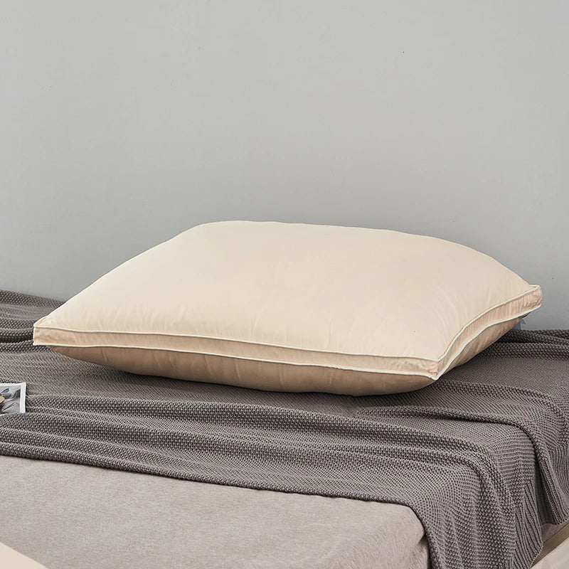A cream-colored luxury goose down and feather bed pillow resting on a gray blanket.
