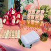 Pink themed party display featuring organza gift bags, jewelry, and candy storage on a pink table.