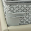 A close-up of a gray bed sheet corner tightener clip with a patterned fabric background.