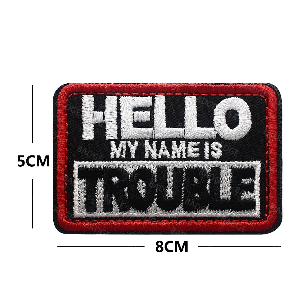 Black and red embroidered patch with white text reading HELLO MY NAME IS TROUBLE