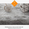 A close-up of a gray fluffy floor mat with a geometric pattern, featuring a mug and a pillow.