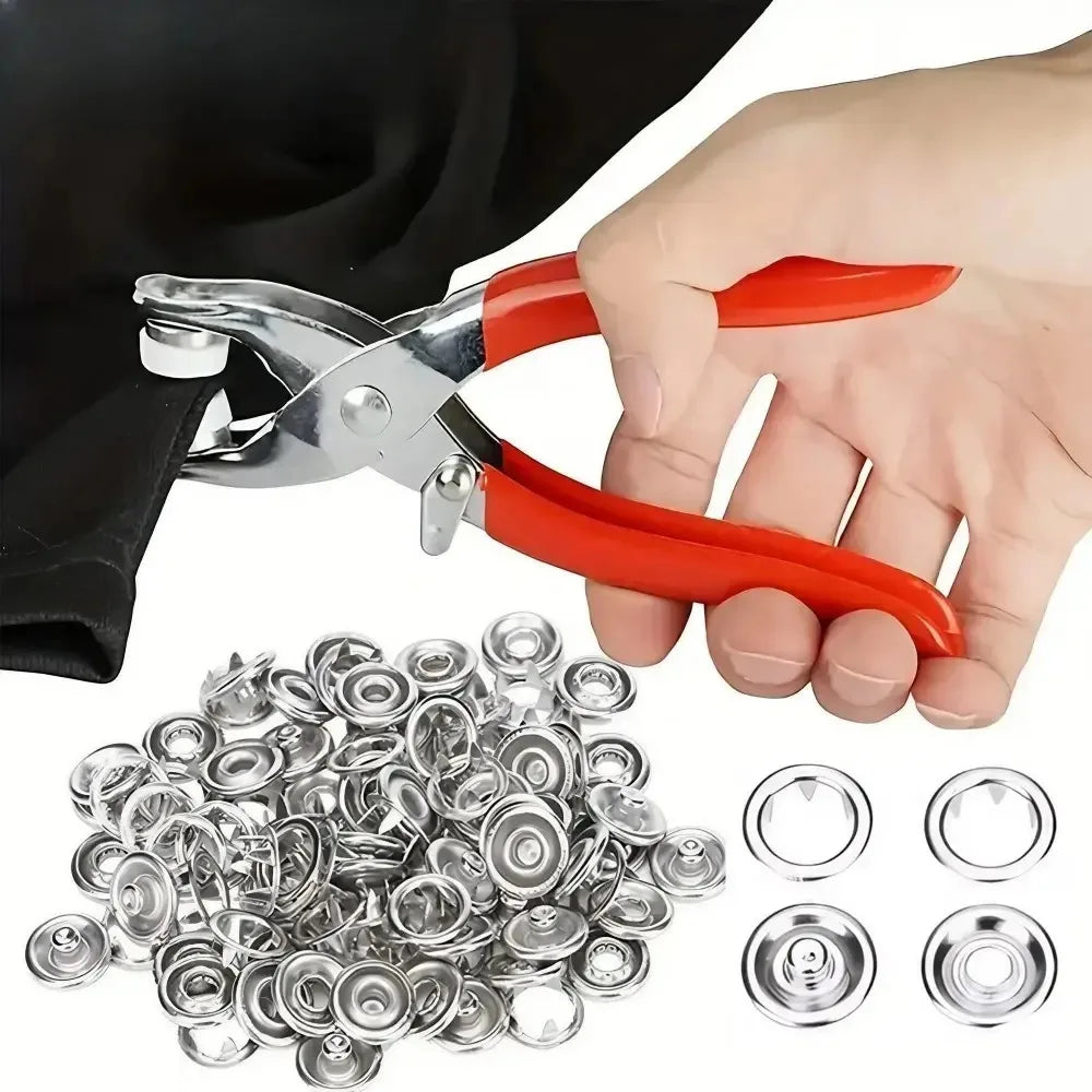 A hand holds a pair of red and silver pliers, next to a pile of metal snap buttons and several loose buttons.