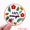 An embroidered patch featuring a red flower and green leaves with the text I AM enough on a white background.