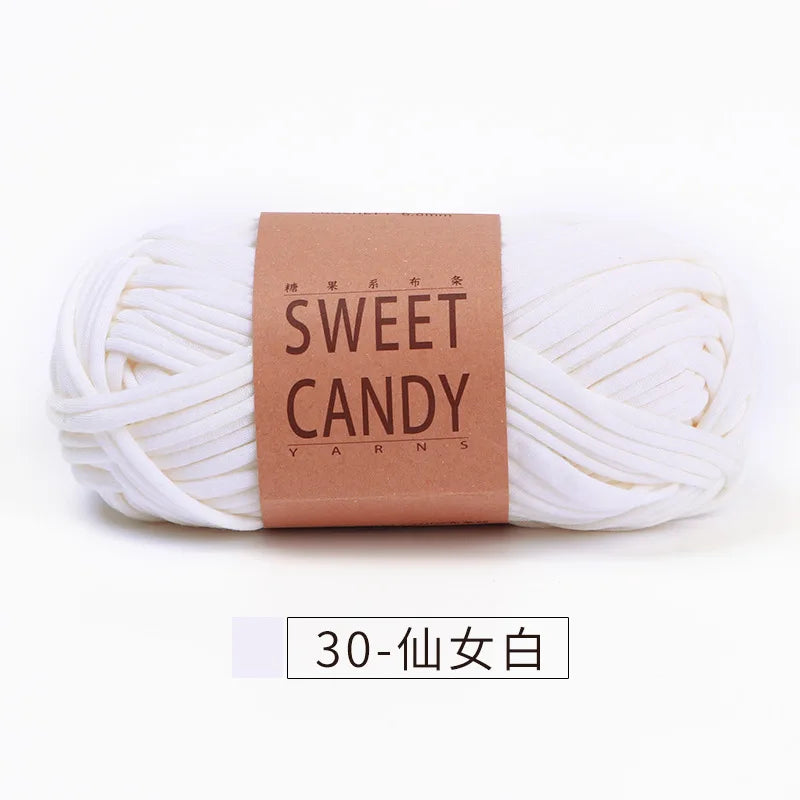 A skein of white yarn labeled Sweet Candy Yarns with a brown tag and Japanese text.