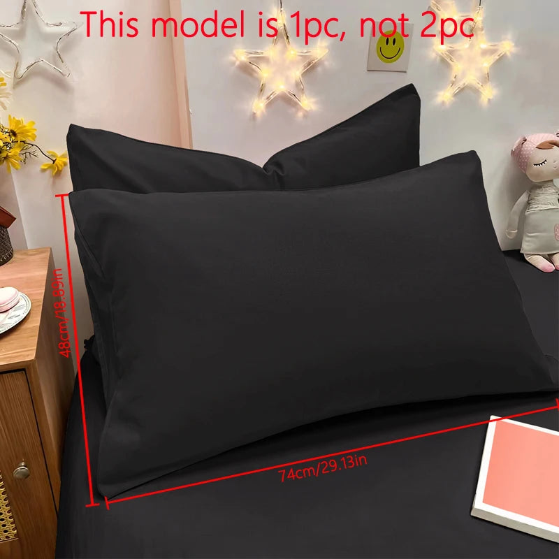 A black matte solid color pillowcase is shown on a bed with decorative star lights and a small plush toy.