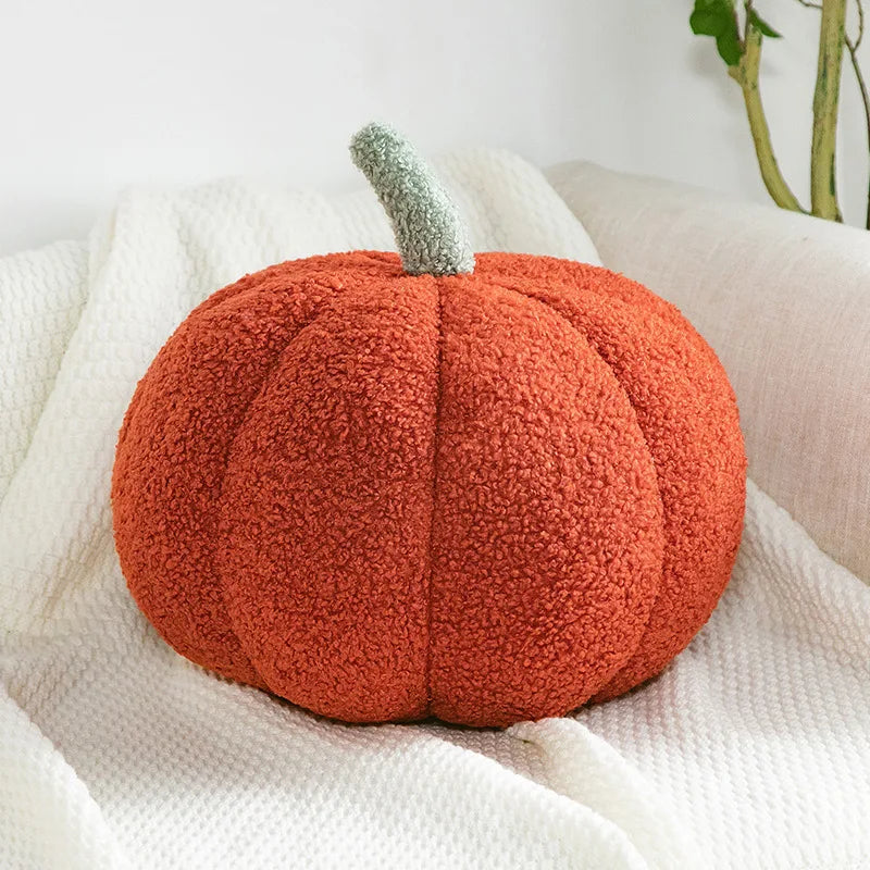 An orange, fuzzy pumpkin plush decoration resting on a white textured fabric.