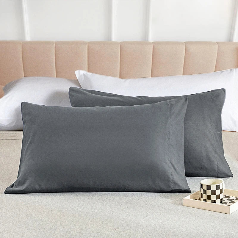 A stack of solid gray microfiber pillow covers resting on a light beige surface.