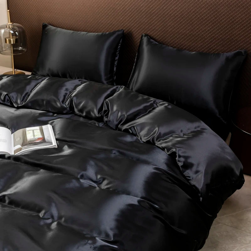 Black satin luxury bedding set with ruffled duvet and pillows on a bed.