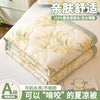 A stack of 100% silk quilted blankets in light green and cream colors for dorms
