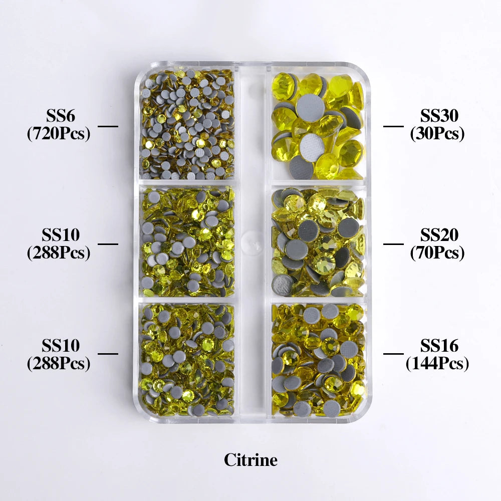 A clear plastic tray containing various sizes of yellow and silver citrine glass rhinestones for crafting.