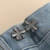 Silver clover-shaped brooches pinned onto a denim fabric