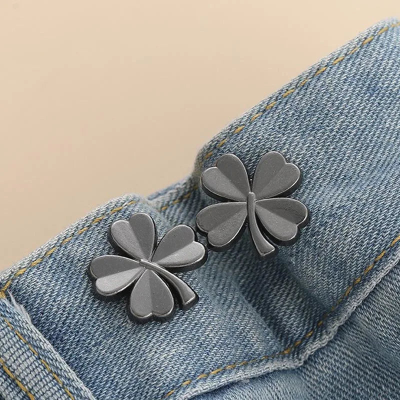 Silver clover-shaped brooches pinned onto a denim fabric