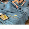 A woman rests on a blue ice silk fiber quilt with a dreamcity design.