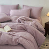 A lilac cotton yarn-dyed duvet cover with matching pillows and a book on a bed.