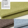 A stack of olive green linen fabric next to a stack of brown and blue linen fabric.