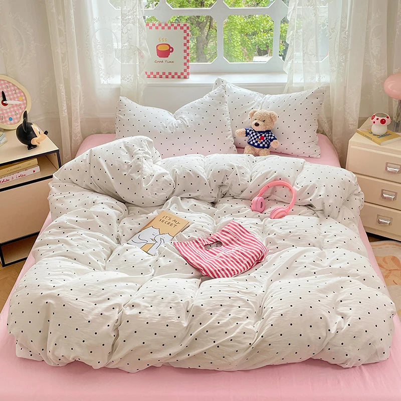 A white microfiber duvet cover set with a pink sheet and pillows is displayed in a bright room.