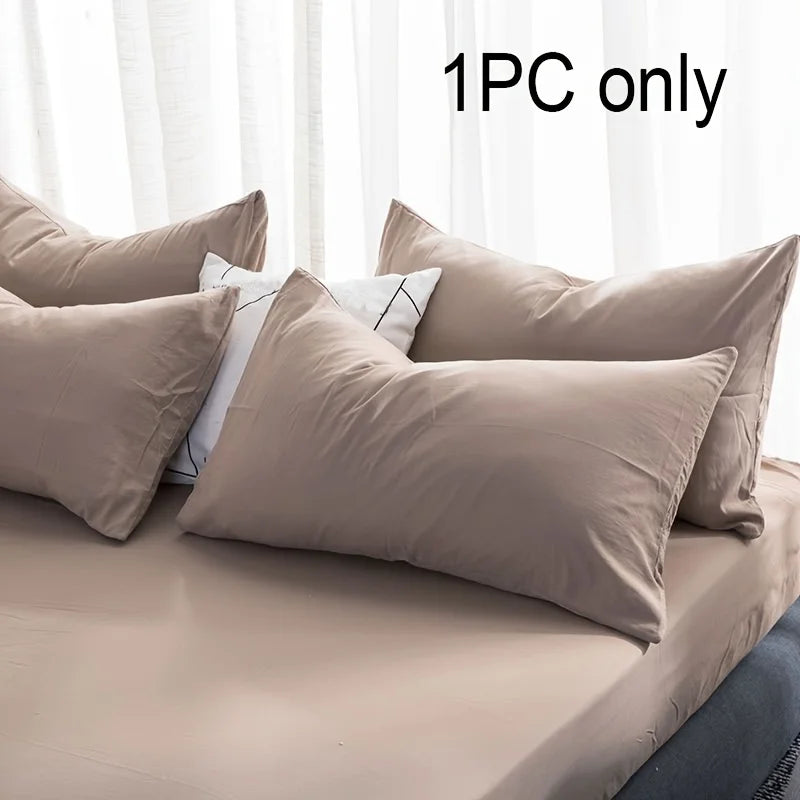 One beige cotton pillowcase with envelope closure shown on a bed.