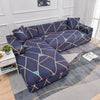 A navy blue L-shaped sofa protector cover featuring a geometric pattern with teal accents on a light gray rug.