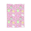 A pink patterned throw blanket featuring cute cats and skulls