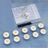 A silver button pin is placed on a translucent pouch with other similar pins scattered below.