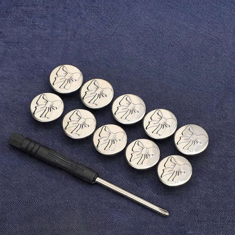 A set of silver metal snap buttons with floral designs arranged on a dark blue fabric.
