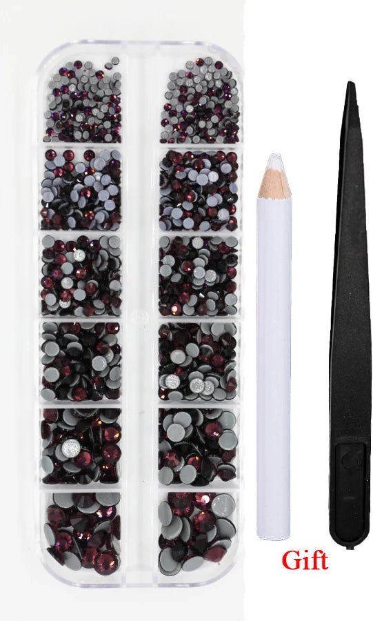 A clear plastic container holds various shades of dark red and black crystal rhinestones for crafting or jewelry making.